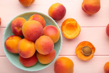 Plate of ripe peaches on pink background. Top view