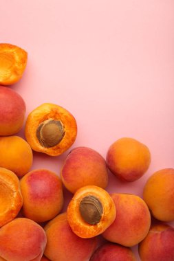 Pembe pastel arka planda taze kayısılar, üst manzara, düz yatış.