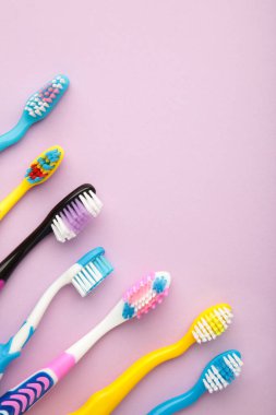 Colorful toothbrushes on purple background. Vertical photo. Top view