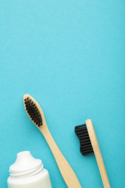 Bamboo toothbrush with toothpaste on blue background. Top view