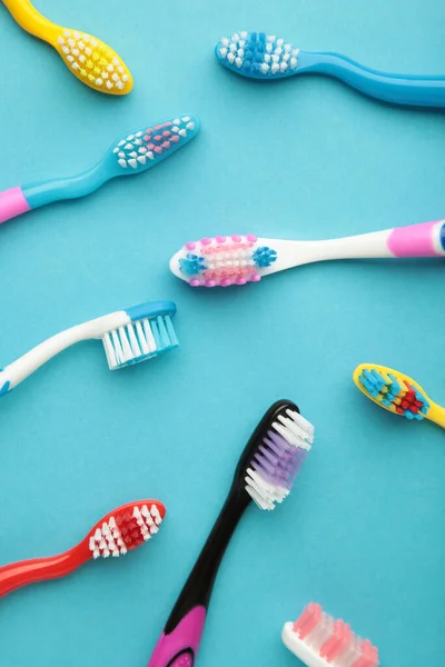 Colorful toothbrushes on blue background. Vertical photo. Top view