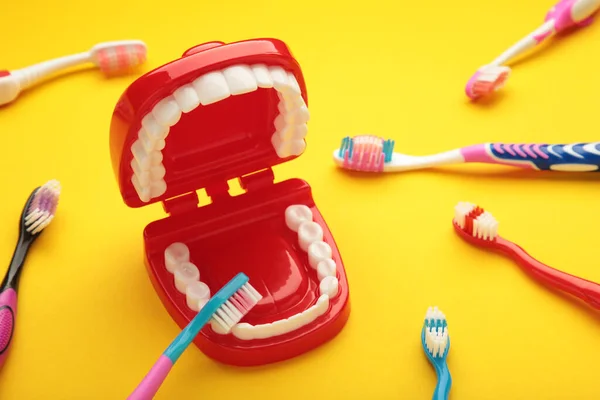 Toy teeth with toothbrush on yellow background. Top view