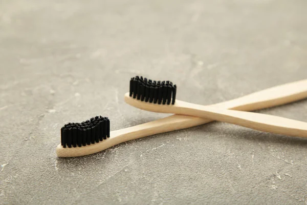 Bamboo wood toothbrush with black brush bristles on grey background. Top view.