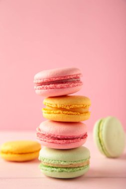Pembe arka planda üç makarondan oluşan dikey bir yığın. Tatlı tatlı. Üst görünüm