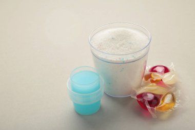 Çamaşır deterjanları, gri arka planda çamaşır tozu ve kapsüller. Üst görünüm