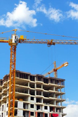 Mavi gökyüzüne karşı binanın yakınında endüstriyel vinç. Şantiye. Endüstriyel arka plan.