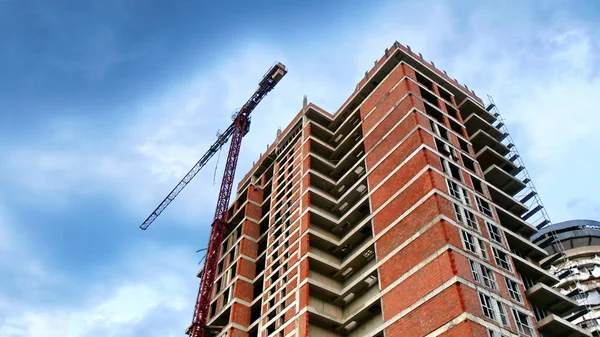 Concrete red building under construction. Construction site. Building site with crane. Industrial background.