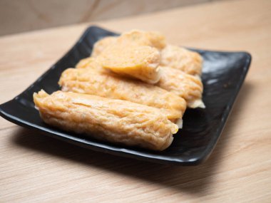 Siyah kare bir kasede bir yığın karides yumurtalı rulo. Tahta masaya ateş et.