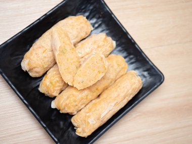 Siyah kare bir kasede bir yığın karides yumurtalı rulo. Tahta masaya ateş et.