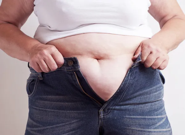 Mujer gorda tratando de usar jeans Imagen de archivo