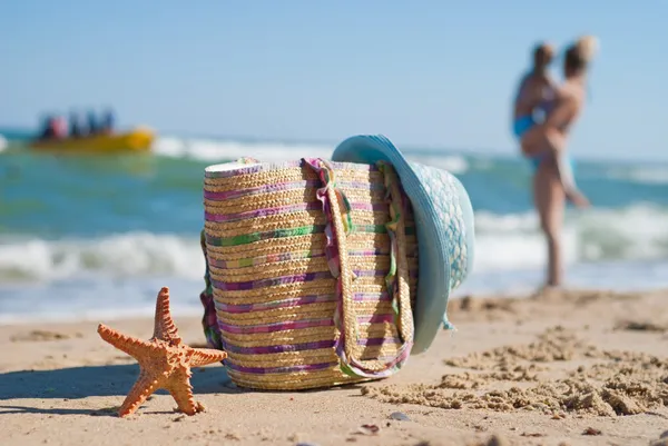 Starfish, beach bag and a woman's hat on the beach. — Stock Photo, Image