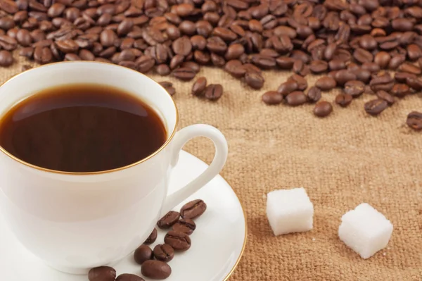Granos de café y una taza en el saqueo — Foto de Stock
