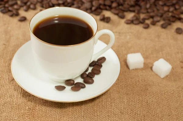 Granos de café y taza en arpillera — Foto de Stock