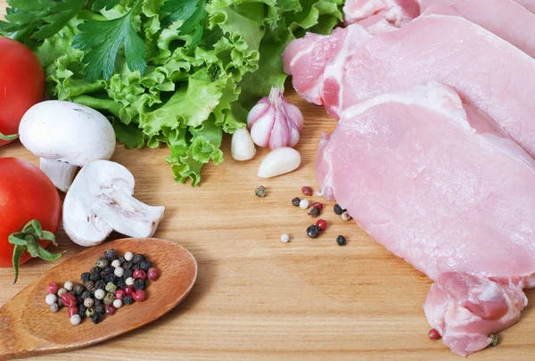 Cocinar carne. Cerdo con verduras sobre tabla de madera . — Foto de Stock