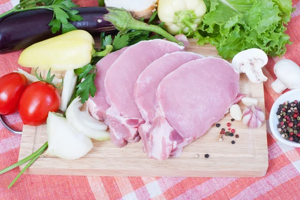 Cocinar carne. Cerdo con verduras sobre tabla de madera . — Foto de Stock