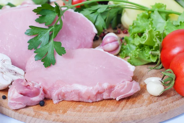 Cocinar carne. Cerdo con verduras sobre tabla de madera . — Foto de Stock