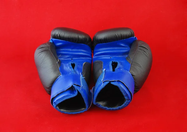 Синие боксерские перчатки на красном фоне — стоковое фото