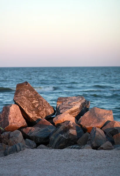 A pile of stones at sunset near the sea beach — Stock Photo, Image
