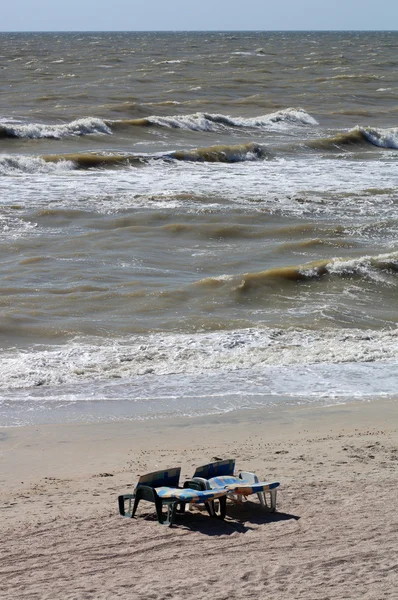 Due sedie a sdraio di plastica vuote sullo sfondo delle onde del mare su — Foto Stock