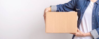 Gri arka planda izole edilmiş kahverengi kutulu Asya teslimat paketi teslim etmek için teslimat paketinin yakın çekim elleri