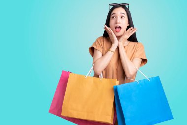 Asyalı bir kadının izole edilmiş mavi arka planda renkli alışveriş çantaları taşıması, yaz indirimi konsepti, alışveriş yapmaktan hoşlanan genç bir kadın.