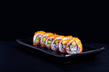 Suşi maki peş peşe somon, karides, avokado, siyah arka planda izole edilmiş krem peynir, Japon restoranı menüsü.