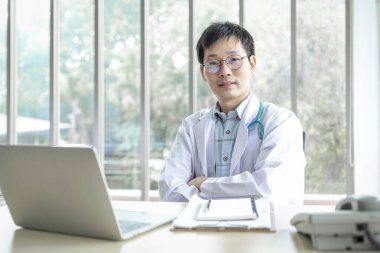 Smiling asian man doctor in the office , Portrait of mature man doctor is committed to treating patients. healtcare and assistance concept