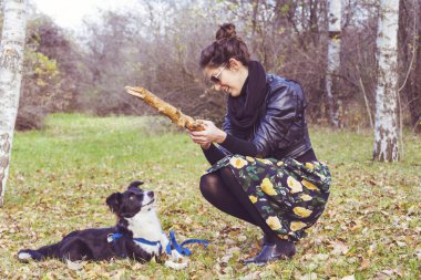 Güz Parkı 'nda evlat edinilmiş Siyah ve Beyaz Köpeğiyle oynayan Güzel Genç Kadın