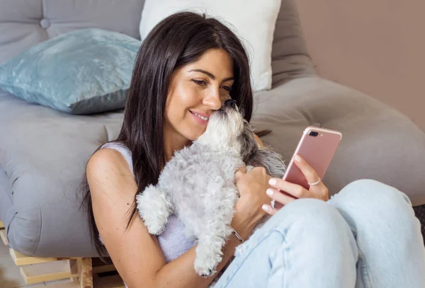 Piękna Uśmiechnięta Kobieta Trzymając Telefon Przytulając Jej Havan Dog Domu — Zdjęcie stockowe