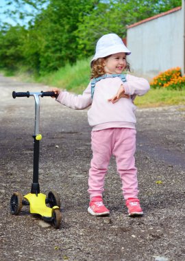 Dışarıda scooter 'ı olan küçük bir kız.