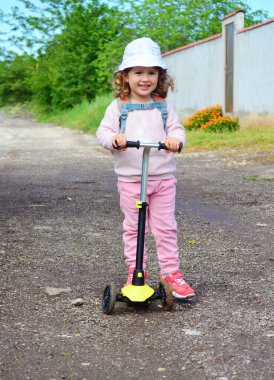 Dışarıda scooter 'ı olan küçük bir kız.