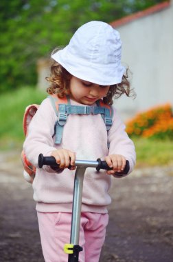 Dışarıda scooter 'ı olan küçük bir kız.