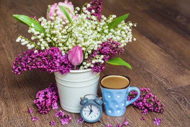 Bir buket beyaz ve mor leylak, bir fincan kahve ve çalar saat. Sabah Kavramı