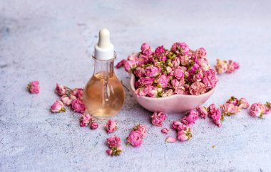 Cam şişede gül yağı ve pembe gül çiçekleri. Gül suyu