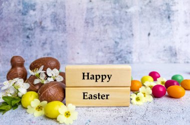 Paskalya Çikolatalı Renkli Yumurtalar ve Kiraz Çiçekleri ile Mutlu Paskalya tebrik kartları. Tahta bloklarda Mutlu Paskalya Metinleri