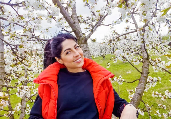 Çiçek açan kiraz ağacında gülümseyen güzel bir kadın.