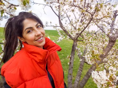 Çiçek açan kiraz ağacında gülümseyen güzel bir kadın.