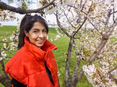 Çiçek açan kiraz ağacında gülümseyen güzel bir kadın.