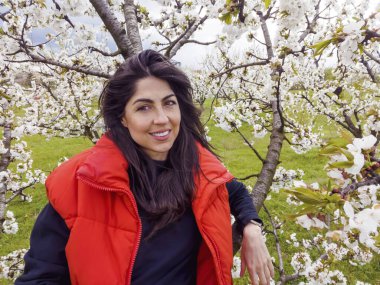 Çiçek açan kiraz ağacında gülümseyen güzel bir kadın.