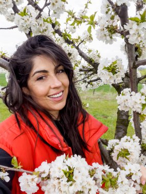 Çiçek açan kiraz ağacında gülümseyen güzel bir kadın.