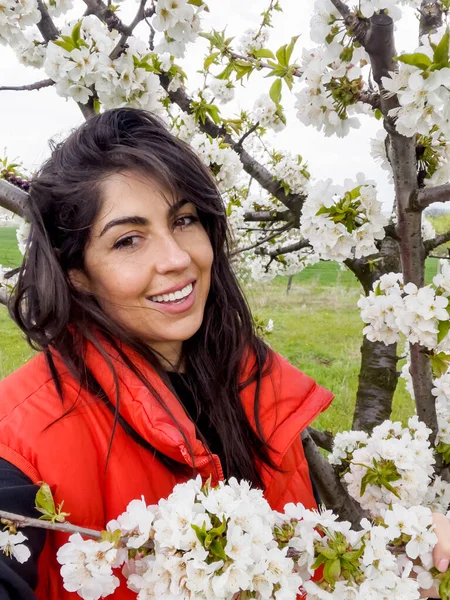 Çiçek açan kiraz ağacında gülümseyen güzel bir kadın.