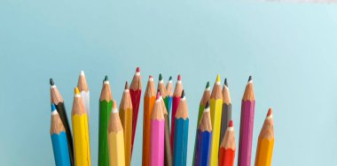 Pastel mavi arkaplanda kopyalama alanı olan renkli kalemler