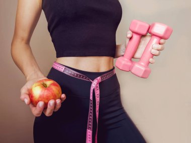 Elinde mezura ve elma olan sıska, tanınmayan bir kadın. Kilo kaybı ve sağlıklı yaşam tarzı kavramı.