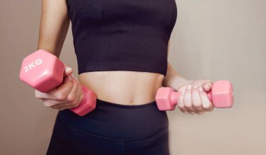 Elinde pembe dambıllar tutan sıska bir kadın. Kilo kaybı ve sağlıklı yaşam tarzı kavramı.