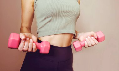 Elinde pembe dambıllar tutan sıska bir kadın. Kilo kaybı ve sağlıklı yaşam tarzı kavramı.