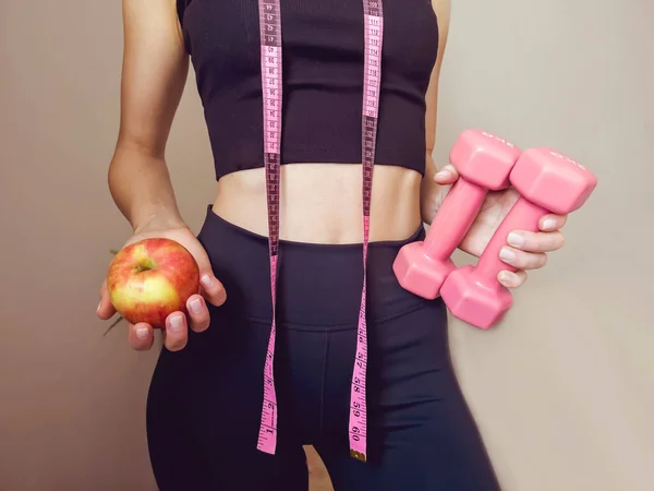 Slim unrecognizable woman with tape measure and apple in the hand .Weight Loss And Healthy Lifestyle Concept