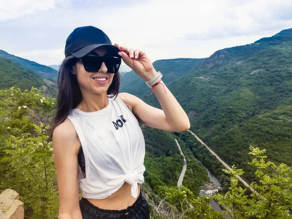 young woman with backpack and sunglasses on the mountain