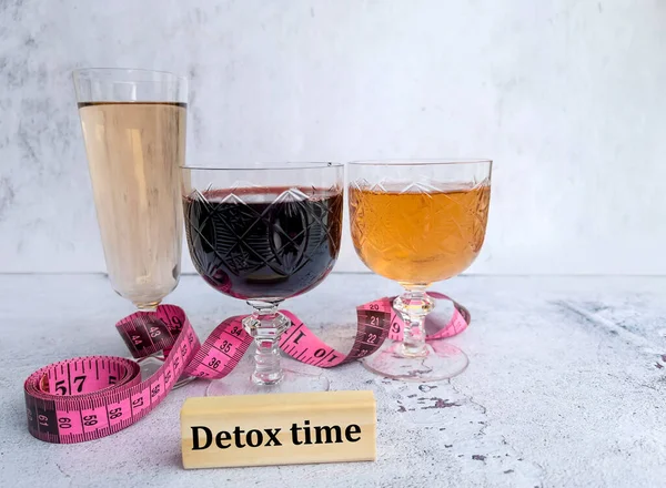 Glasses of wine and rose with measuring tape and detox time message on wooden cubes