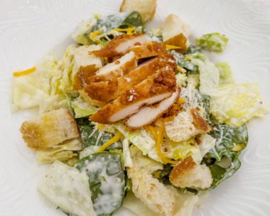 Sezar salatası ve tavuklu beyaz tabak.