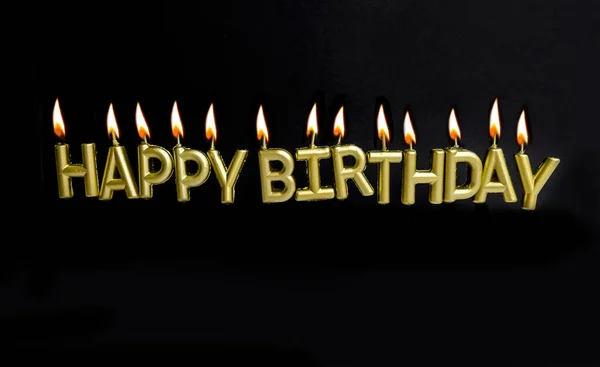Golden Happy birthday sign with candles on black background